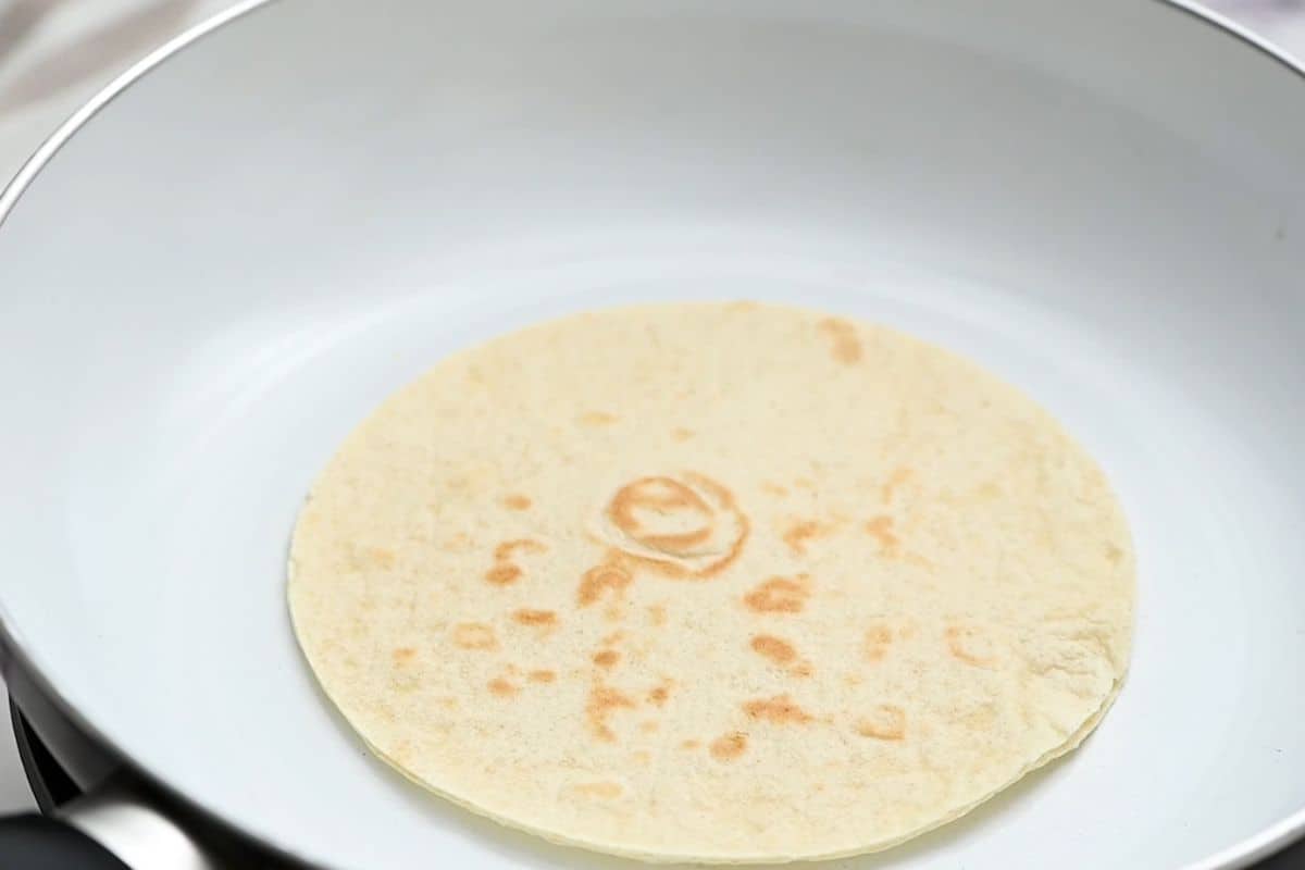 Flour Tortilla in frying pan after being toasted briefly.