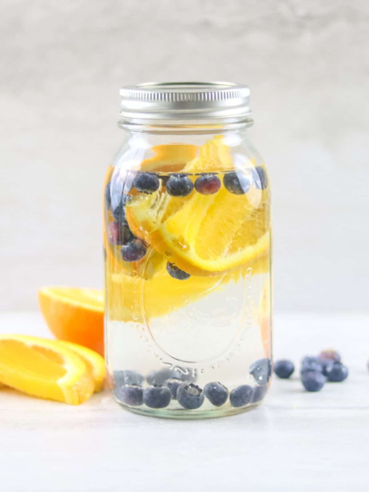 Mason Jar with Water infused with Blueberries and Orange Slices.