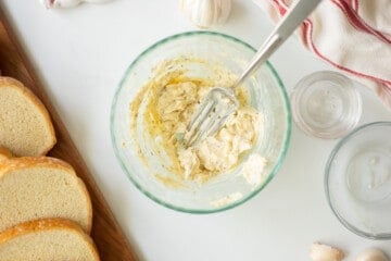 Garlic Butter mashed together in bowl with fork and thick bread to the side.