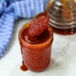 Jar of homemade BBQ sauce in jar with spoon coming out of it.
