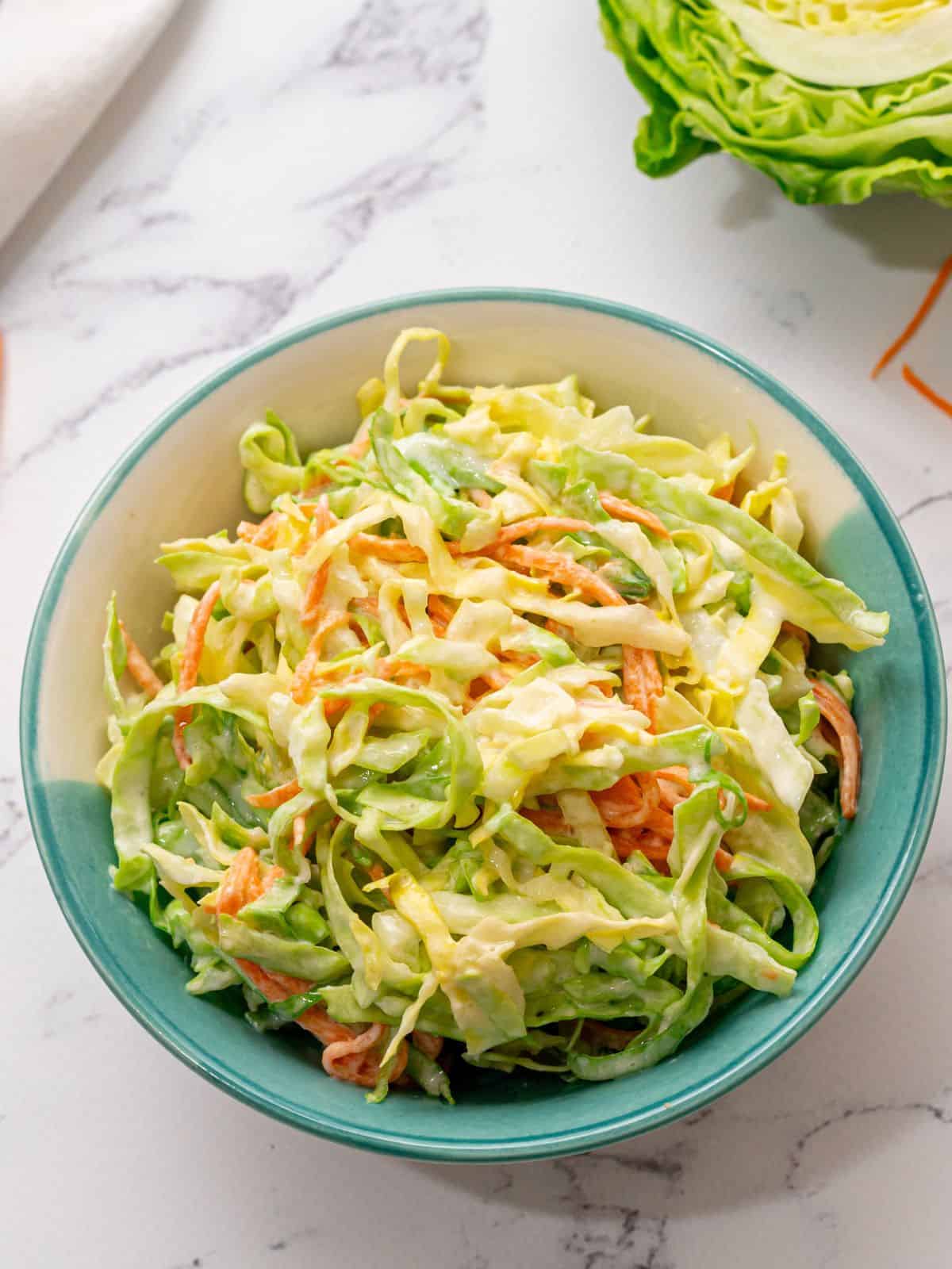 Bowl of homemade creamy coleslaw on white counter.