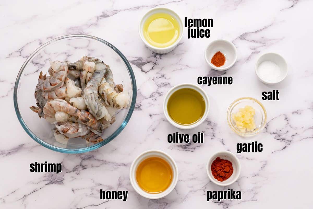 Ingredients for grilled shrimp and honey lemon marinade on counter with text.
