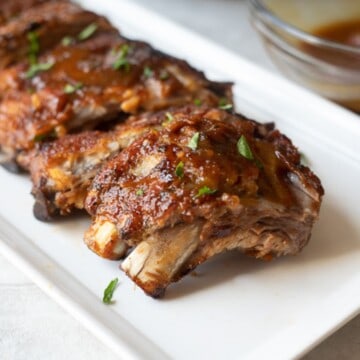 Instant Pot Ribs on platter topped with BBQ sauce.
