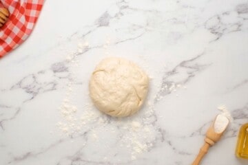 Homemade pizza dough on floured surface after kneading.