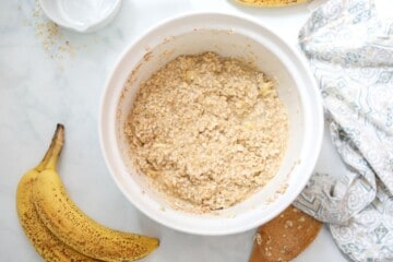 Ingredients for banana baked oatmeal mixed together in large white mixing bowl.