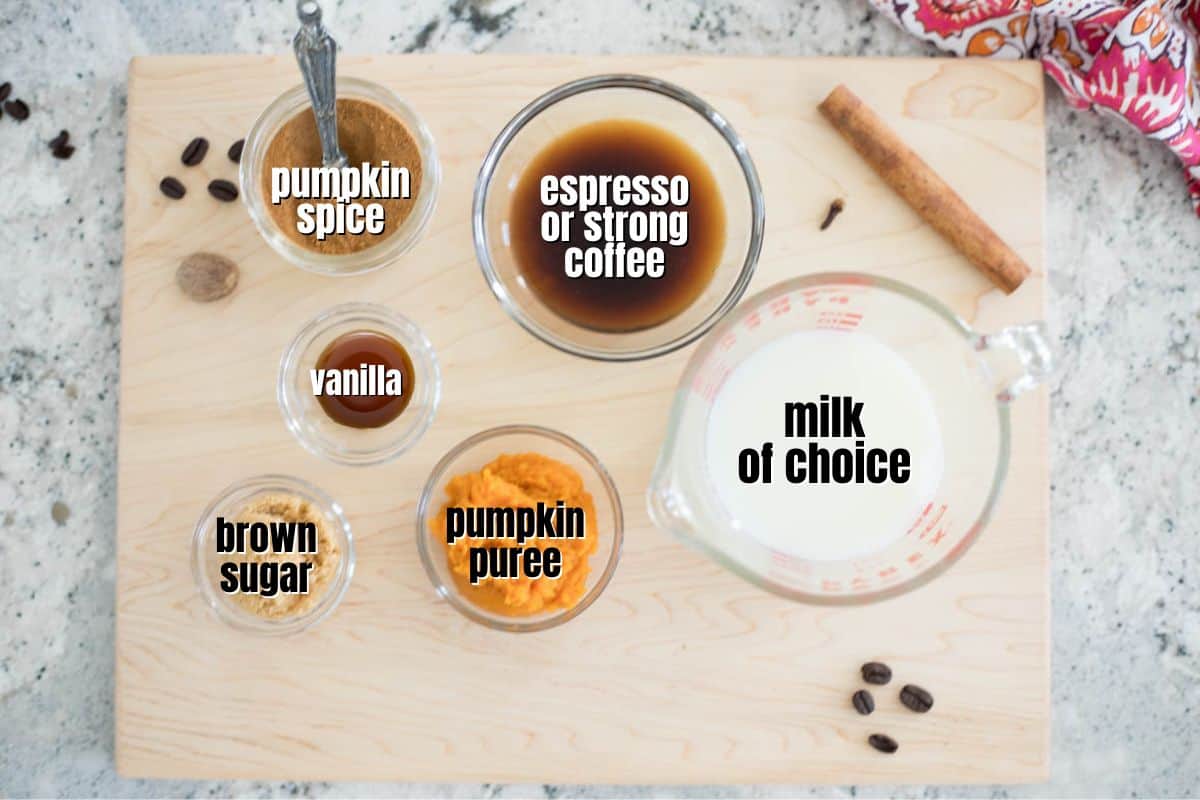 Ingredients for pumpkin spice latte labeled on wooden cutting board.