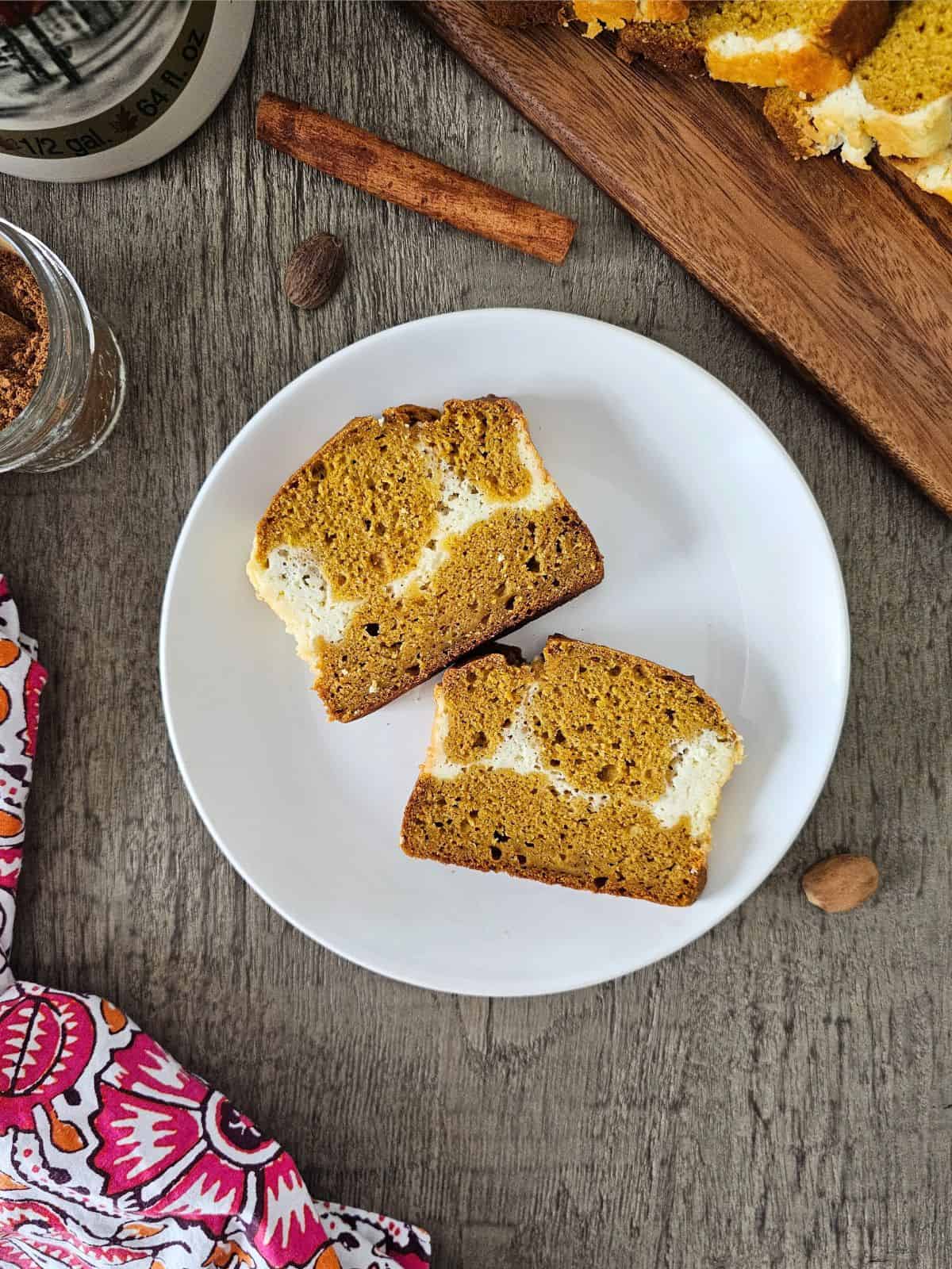 Two slices of pumpkin cream cheese bread on a white plate.