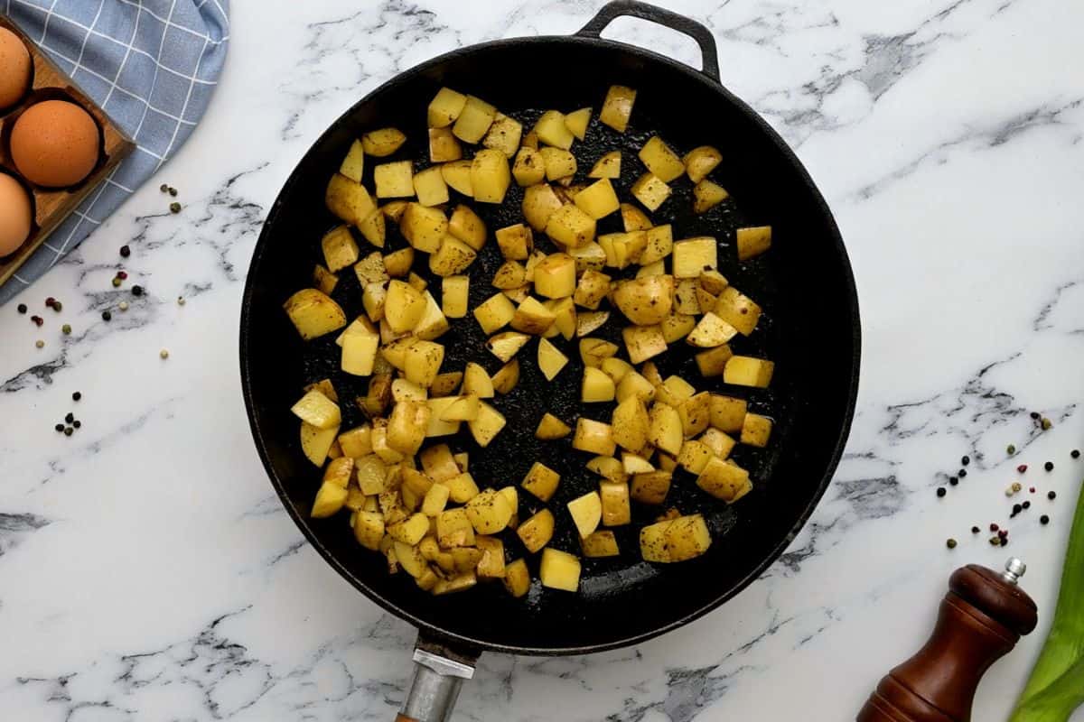 Sauteed potatoes in skillet seasoned with salt and pepper.