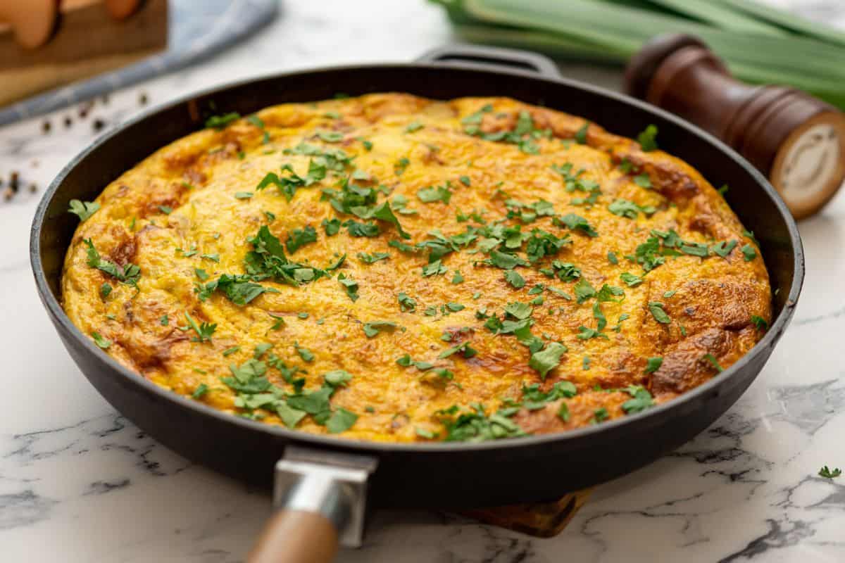 Baked Frittata with potatoes and bacon in oven-safe skillet.