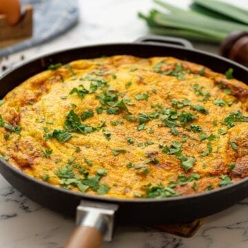 Baked potato frittata in skillet topped with fresh parsley.