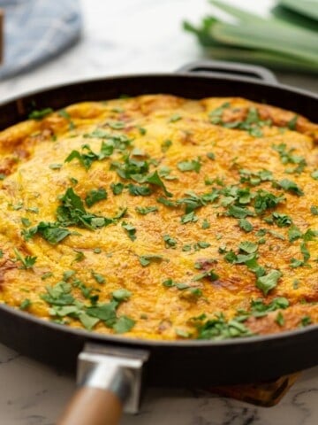 Baked potato frittata in skillet topped with fresh parsley.
