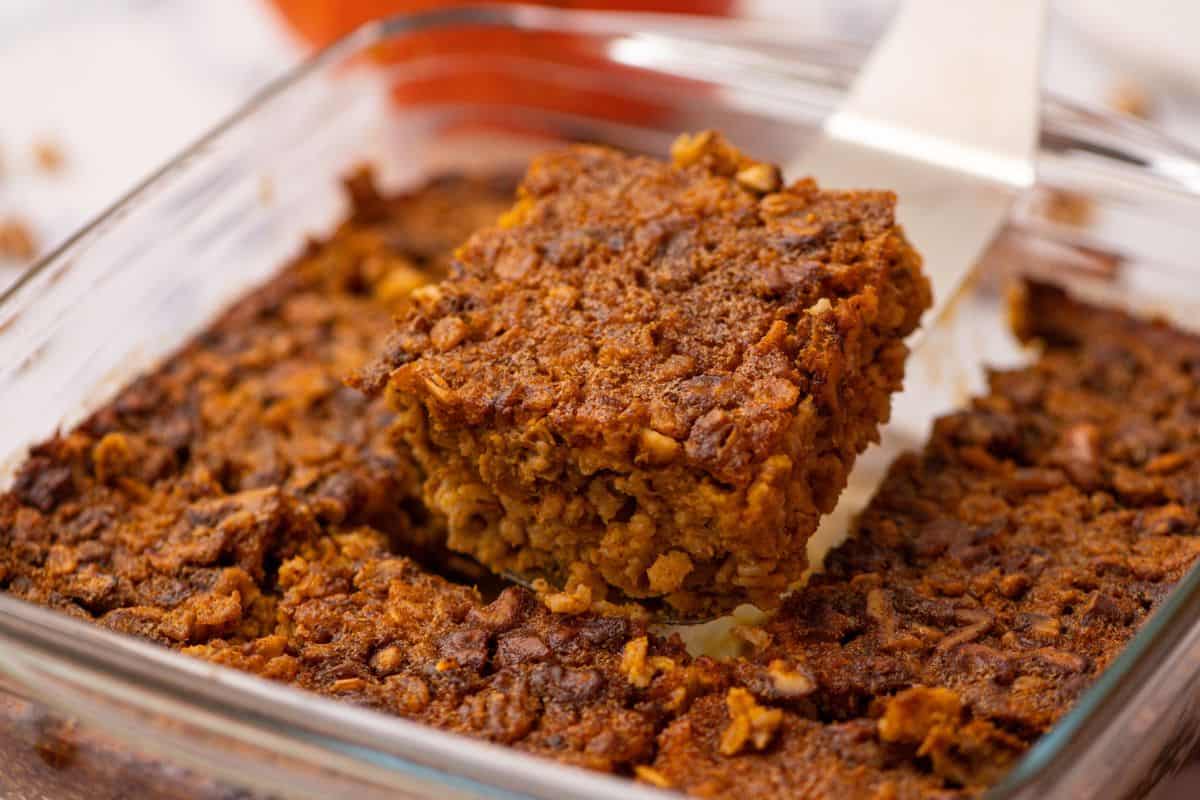 Baked Pumpkin Oatmeal in glass baking dish with spatula removing one slice.