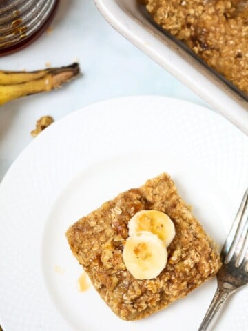 Slice of banana baked oatmeal on plate next to fork.