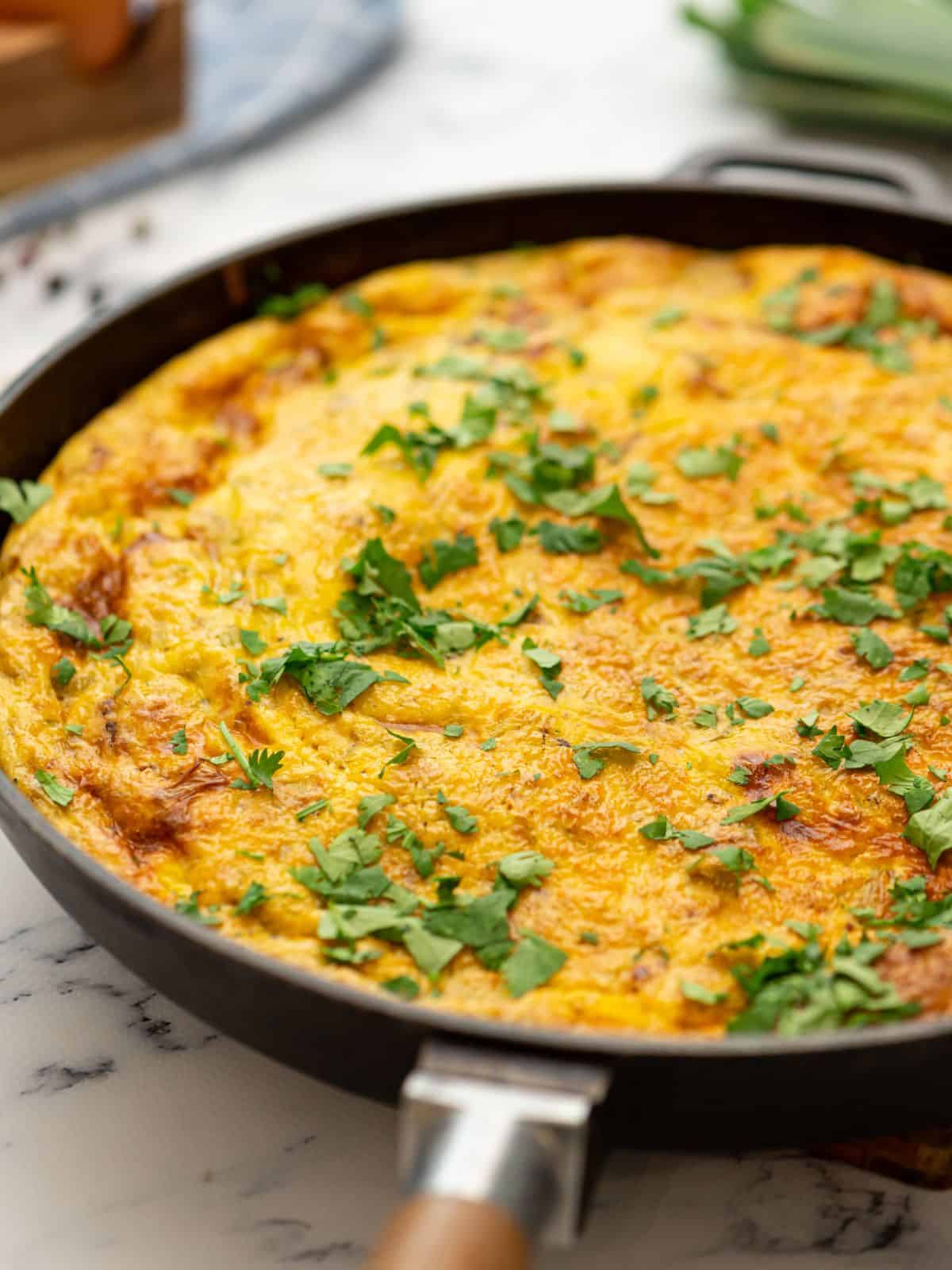 Baked Frittata with potatoes and bacon in oven-safe skillet.