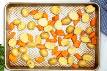 Seasoned potatoes and carrots spread out on sheet pan.