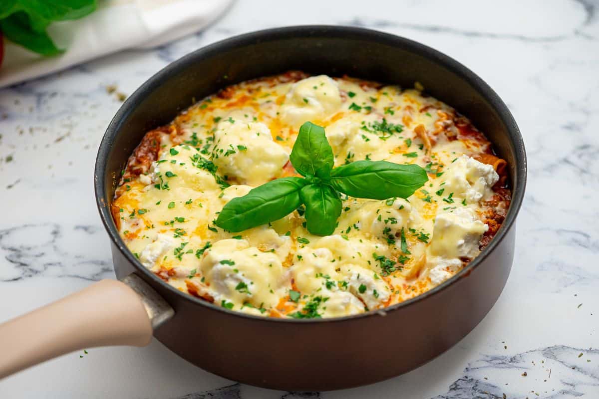 Skillet lasagna cooked in large deep skillet topped with basil.