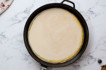 Batter for Dutch Oven Pancake poured in greased skillet.