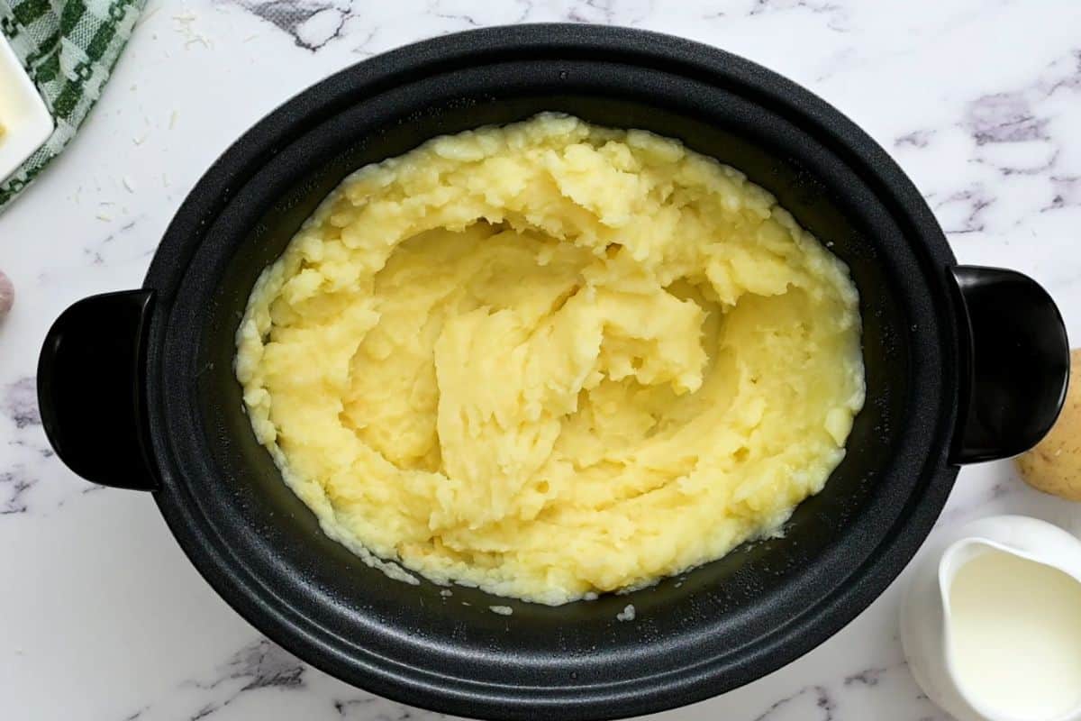 Crockpot filled with mashed potatoes after slow cooking.