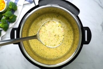 Ladle scooping out creamy broccoli cheddar soup from inner pot of instant pot.