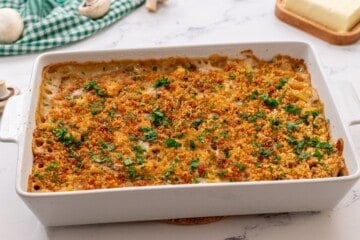 Baked turkey tetrazzini in white casserole dish topped with minced parsley.