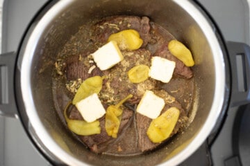 Ingredients for Mississippi Pot Roast in inner pot topped with pats of butter.