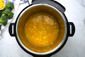 Inner pot with broth and sauteed carrots and onions.