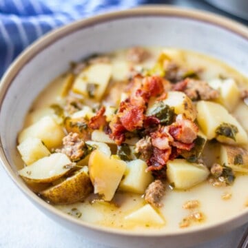 Bowl of Instant Pot Zuppa Toscana topped with bacon and parmesan cheese.