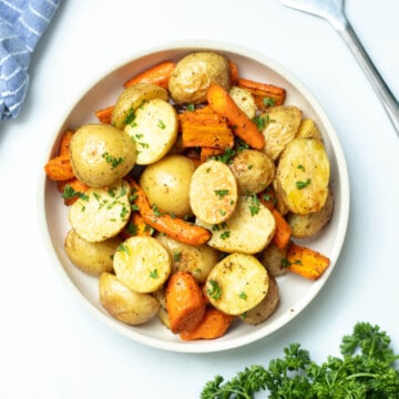 Bowl of roasted potatoes and carrots topped with fresh parsley.