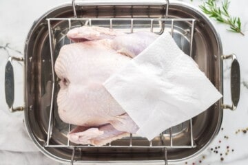 Turkey in roasting pan showing plotting with paper towel to remove excess moisture.