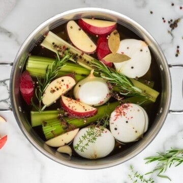 Ingredients for Turkey brine in stock pan with apples, onions, peppercorns, onions, and celery in stock pan.