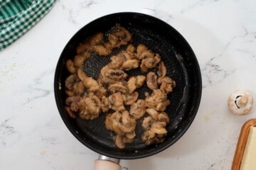 Mushrooms coated in flour in saute pan.