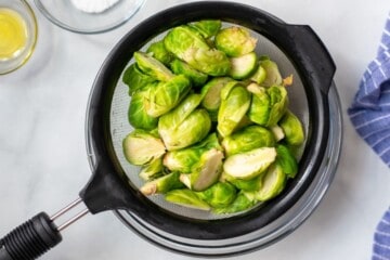 Steamed Brussels sprouts in fine mesh strainer.