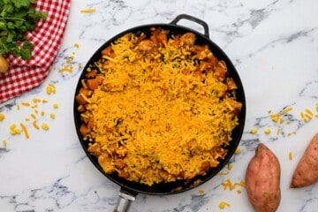 Chicken sweet potato skillet topped with shredded cheese.