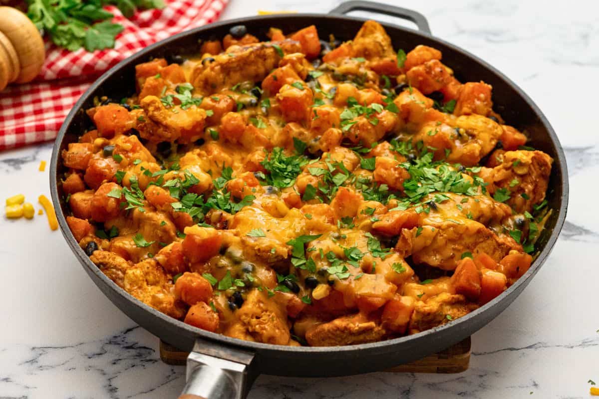 Cheesy Chicken and Sweet Potatoes with Beans and Corn in skillet topped withe cilantro.