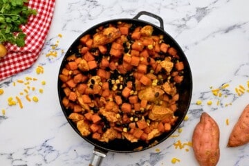 Skillet with sweet potatoes, chicken, corn, and black beans tossed together.