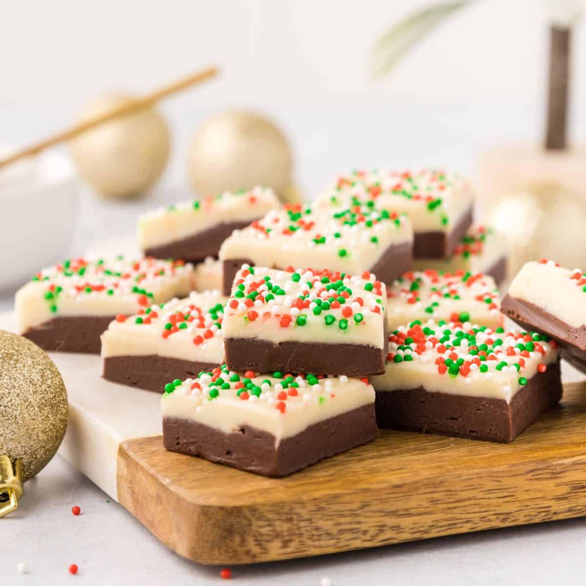 Layered fudge with Christmas sprinkles on cutting board.