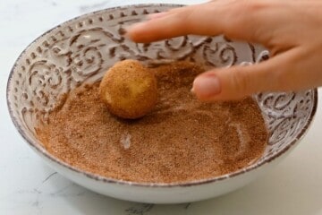 Rolling cookie dough in cinnamon sugar.