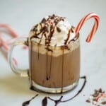 Peppermint mocha in glass mug drizzled with chocolate syrup and crushed peppermint canes.