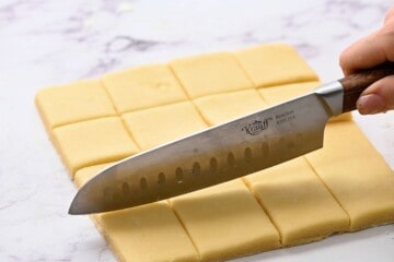 Knife cutting shortbread cookies into squares.