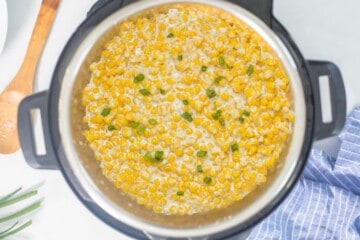 Instant Pot with creamed corn topped with green onions.