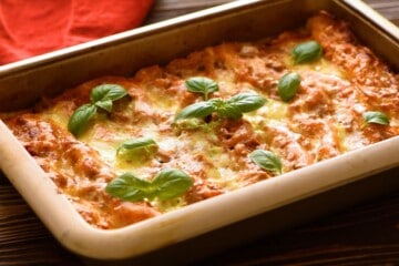Baked Lasagna topped with fresh basil in large baking dish.
