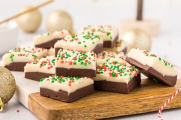 Layered fudge with holiday christmas sprinkles on cutting board.