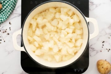 Boiled cubed russet potatoes in saucepan after draining.