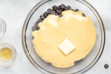 Glass bowl with chocolate chips, sweetened condensed milk, and butter.