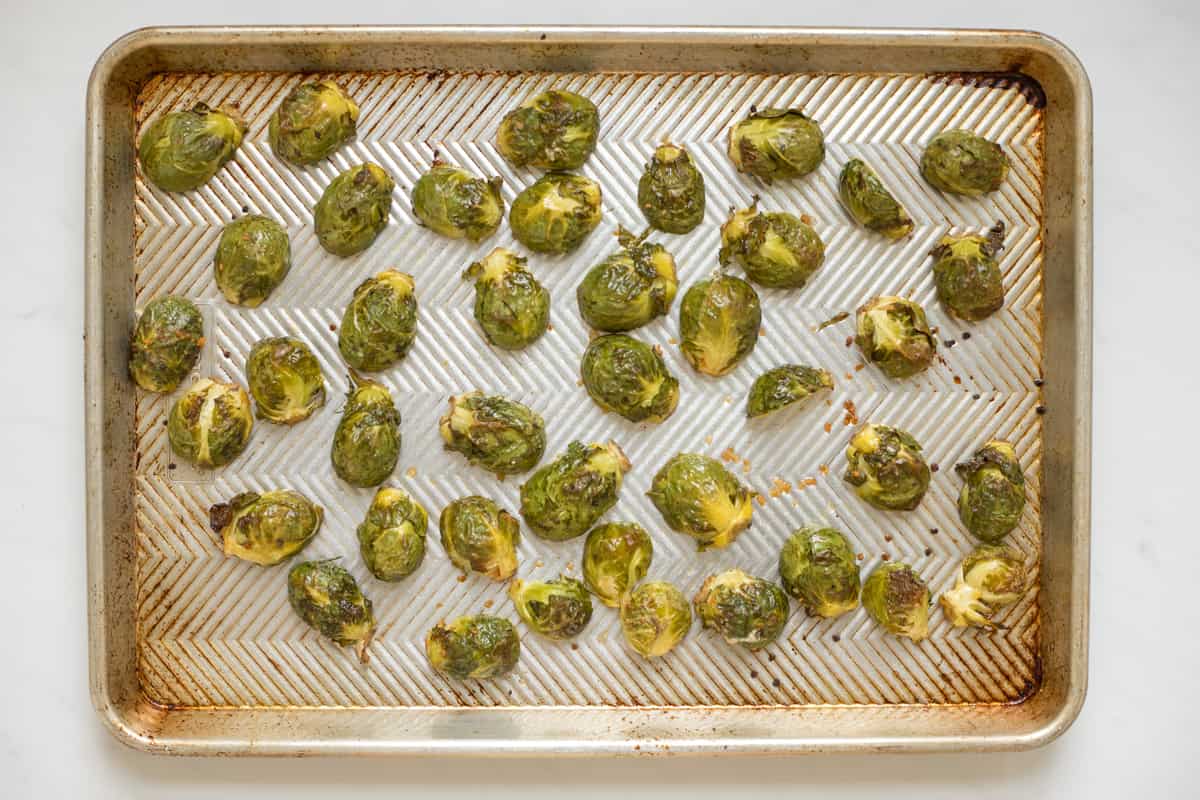 Roasted halved fresh brussels sprouts on sheet pan spread out.