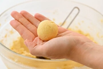 1 tablespoon of snickerdoodle cookie dough rolled into a ball in a hand.