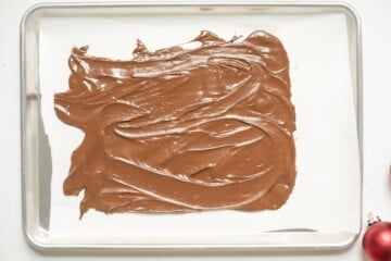 Melted chocolate spread out in thin layer on parchment paper.