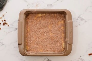 Sour Cream Coffee Cake batter in cake pan with cinnamon swirl sprinkled over batter.
