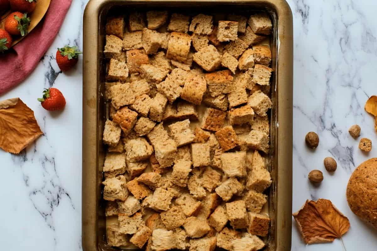 Dairy-Free French Toast Casserole Bread cubes soaked in maple egg custard in butter baking dish.