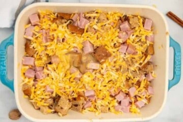 Ham Cheese and Cinnamon Bread layered in blue casserole dish with egg mixture poured over it.